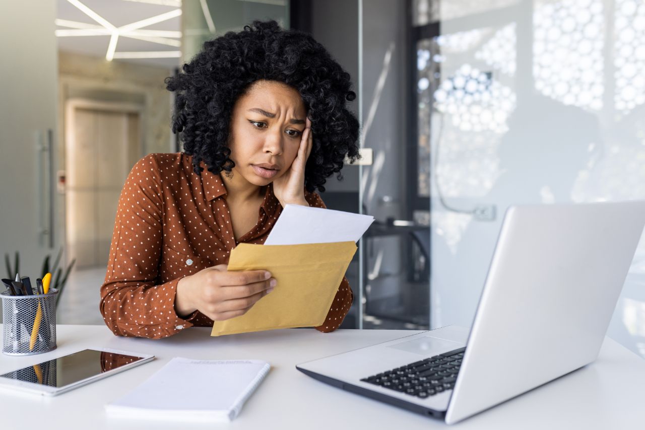 A worried business owner at her desk reading paperwork